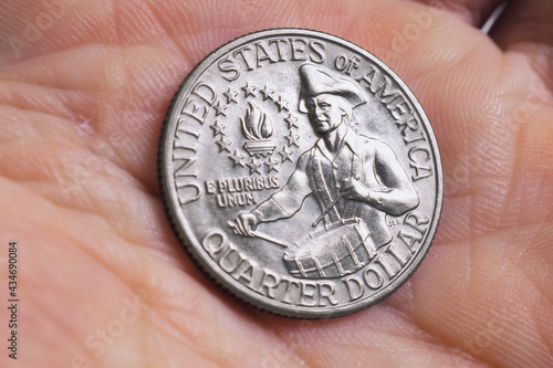 The USA quarter dollar coin with drummer lies in a man's palm close up. Illustration on the theme of American patriotism and Independence Day July 4. Macro
