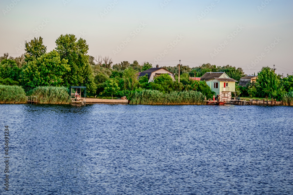 View of the holiday village on the banks of the Konka River in Kherson (Ukraine). View from the water to the coastline with private houses and piers among the reeds View of the holiday village on the banks of the Konka River in Kherson (Ukraine). View from the water to the coastline with private houses and piers among the reeds