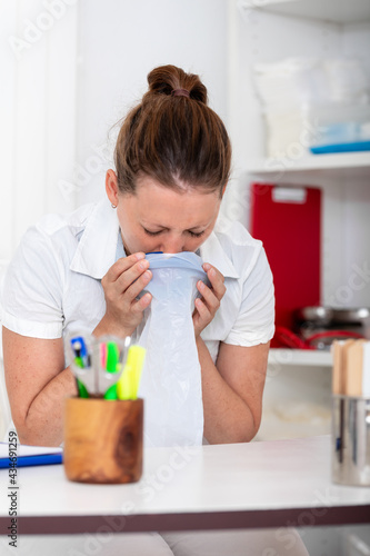 Canvas Print a female nurse or doctor is vomiting into a bag