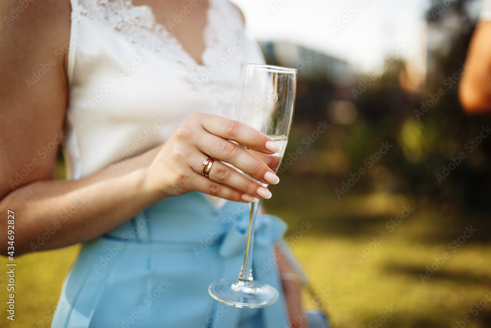 A glass of champagne in the hands of a girl at the party. Woman with a glass of wine in her hands. Summer holiday, birthday, anniversary, wedding. A glass of champagne in the hands of a girl at the party. Woman with a glass of wine in her hands. Summer holiday, birthday, anniversary, wedding.