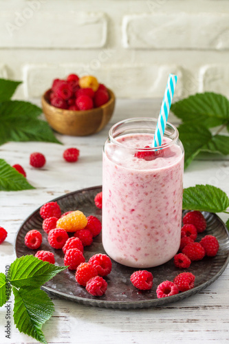 Summer cool milkshake. Raspberry protein shake in glass and fresh raspberry on a wooden table.