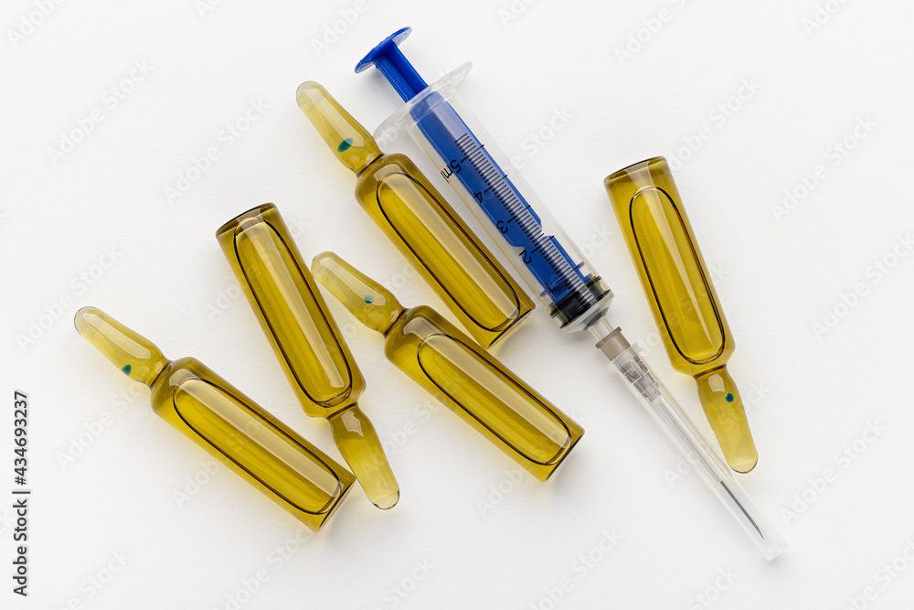 Disposable blue syringe and ampoules with medicine on a white background, close-up. Health concept. Disposable blue syringe and ampoules with medicine on a white background, close-up. Health concept.