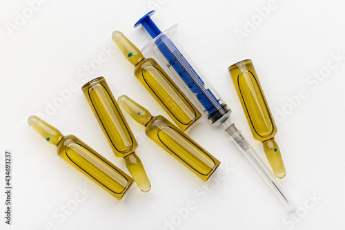 Disposable blue syringe and ampoules with medicine on a white background  close-up. Health concept.