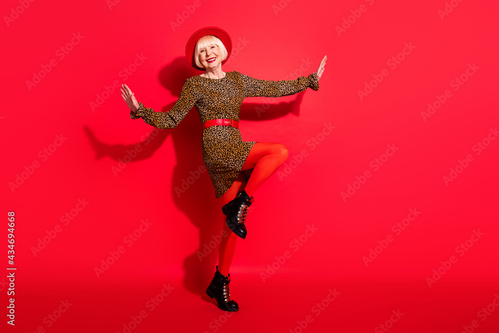 Full body photo of cheerful aged woman happy positive smile enjoy music dance isolated over red color background Full body photo of cheerful aged woman happy positive smile enjoy music dance isolated over red color background