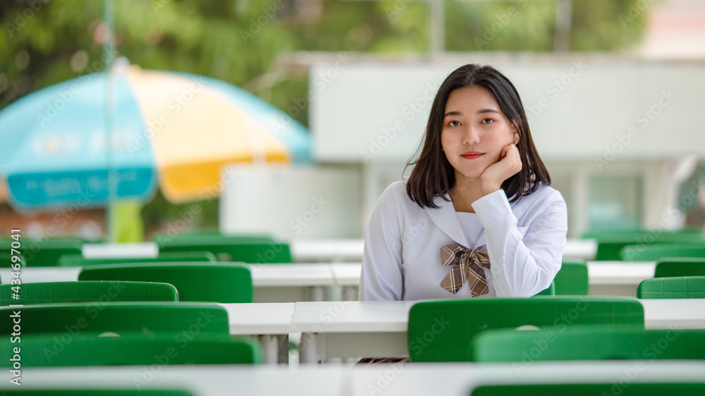 Calm Asian student at table in university garden Calm Asian student at table in university garden