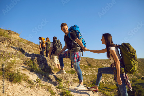 Group of tourists on hiking trip in mountains, copy space text. Team of active young people with backpacks mountaineering outdoors photo