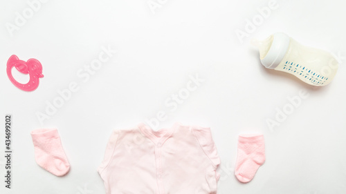 baby bottle with milk and clothes with accessories for kids on white background top view. Space for text