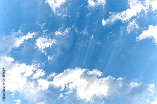 blue sky with white fluffy clouds and sun rays © VeKoAn