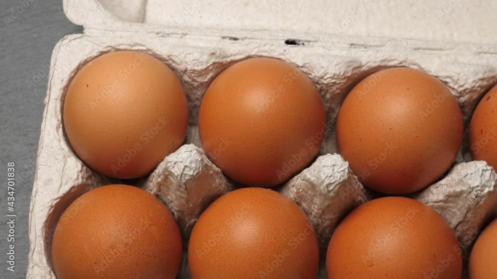 Uncooked eggs in pack. Rotating on black slate background. Closeup Uncooked eggs in pack. Rotating on black slate background. Closeup