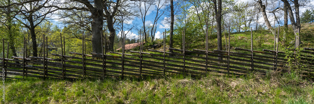 Old traditional swedish wooden fence. Vintage style hedge. Countryside farm authentic cozy hand made wooden fence palisade in a rural area. Scandinavian rural houses interior details.