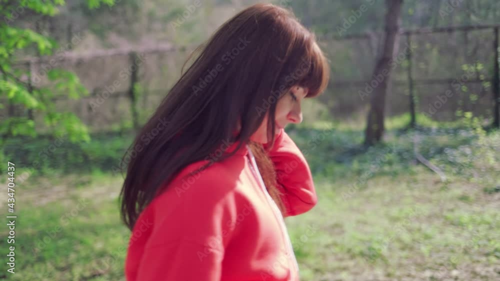A young Caucasian woman walks through a summer park. Side view. Truck shot. A young Caucasian woman walks through a summer park. Side view. Truck shot.