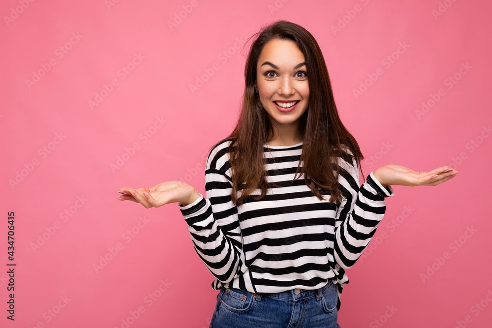 Photo of young positive happy beautiful brunette woman with sincere emotions wearing casual striped pullover isolated on pink background with copy space Photo of young positive happy beautiful brunette woman with sincere emotions wearing casual striped pullover isolated on pink background with copy space