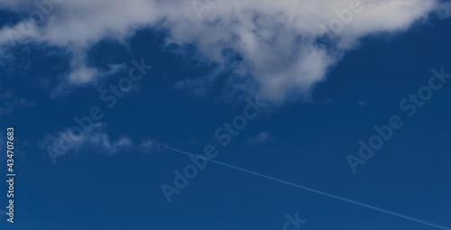 Blue sky with clouds and white plane with white smoke trail. White smoke.