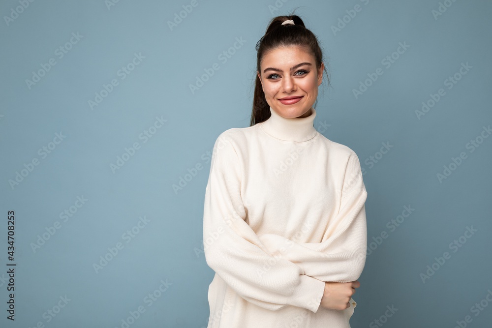 Lovely smiling young woman wearing warm sweater standing isolated over blue background, posing Lovely smiling young woman wearing warm sweater standing isolated over blue background, posing