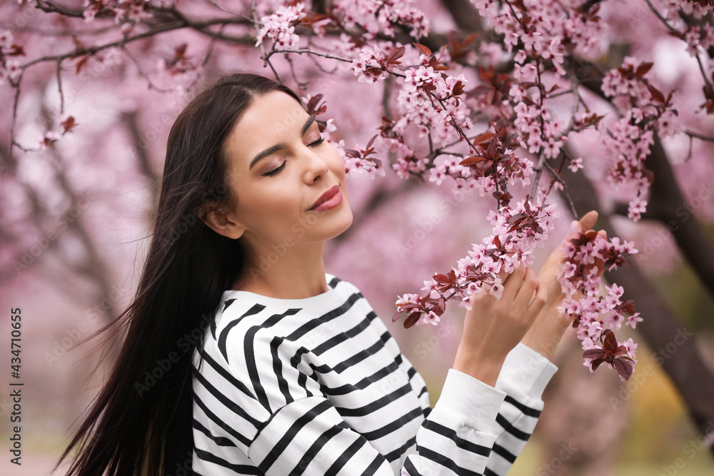 Pretty young woman near blooming tree in park. Spring look Pretty young woman near blooming tree in park. Spring look
