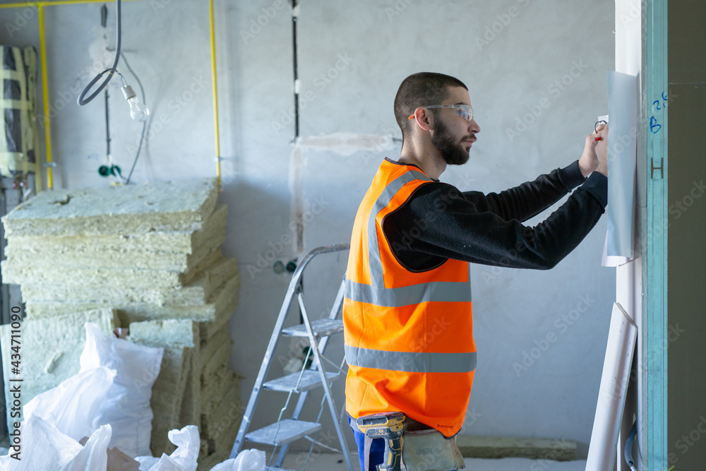 Male worker holding a paper apartment plan indoor before repair room Male worker holding a paper apartment plan indoor before repair room