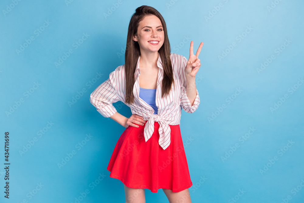 Portrait of attractive fashionable cheerful girl showing v-sign posing good mood isolated over bright blue color background Portrait of attractive fashionable cheerful girl showing v-sign posing good mood isolated over bright blue color background