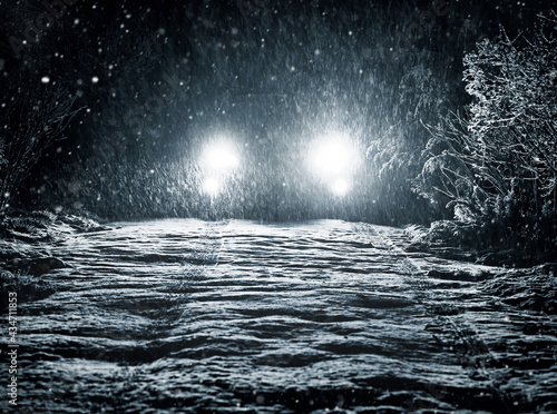 Fototapeta Naklejka Na Ścianę i Meble -  Snow falls on the road in the headlights