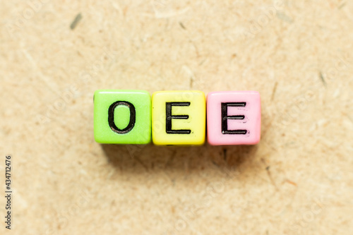 Color alphabet letter block in word OEE (abbreviation of overall equipment effectiveness) on wood background photo