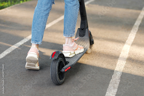 an electronic scooter and a girl on a walk in a city park in the summer. close-up