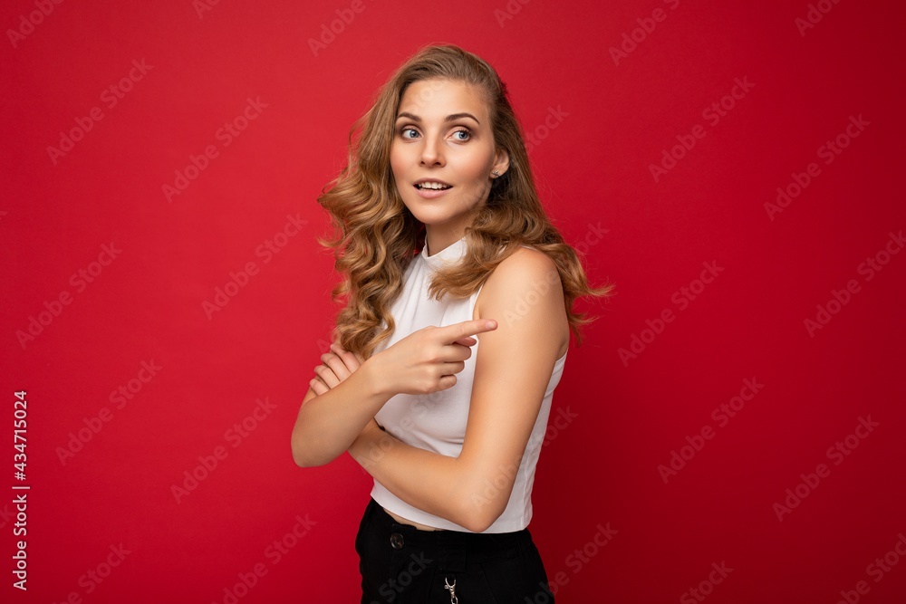 Portrait photo of young beautiful pretty positive self-confident assertive cool blonde woman with sincere emotions wearing stylish white top isolated over red background with free space and pointing Portrait photo of young beautiful pretty positive self-confident assertive cool blonde woman with sincere emotions wearing stylish white top isolated over red background with free space and pointing