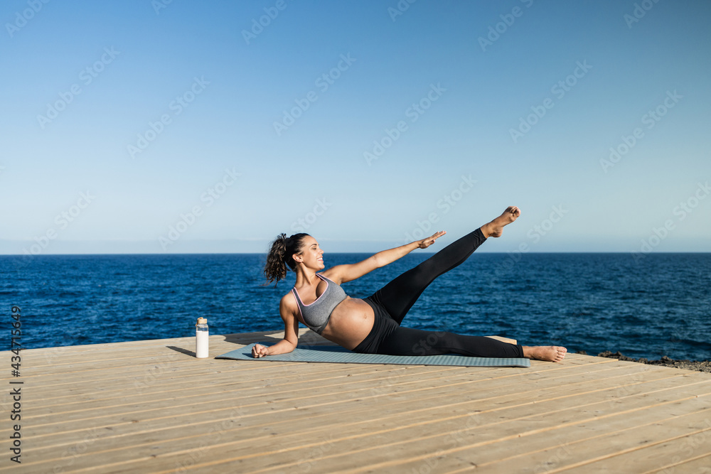Young pregnant woman doing yoga outdoor - Sport exercises and maternity concept for an healthy lifestyle - Focus on face