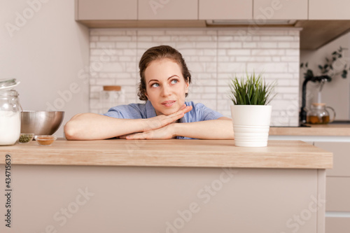 Portrait of young thinking female on kitchen interior background. Looking aside.