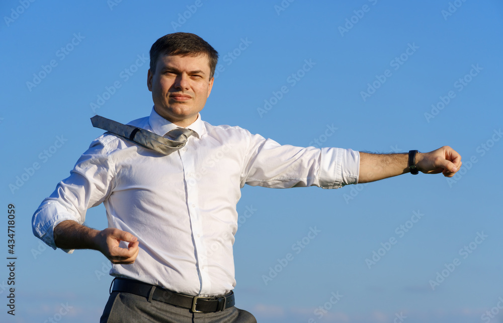 businessman posing in a field, he goes in for sports and does strikes like martial arts or superman, green grass and blue sky as background