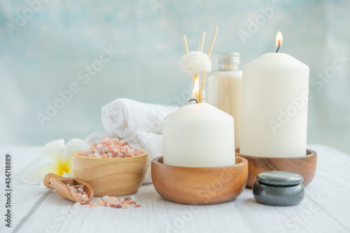 Natural relaxing spa composition on massage table in wellness center with towels, flowers and salt, candle on massage table in spa salon.