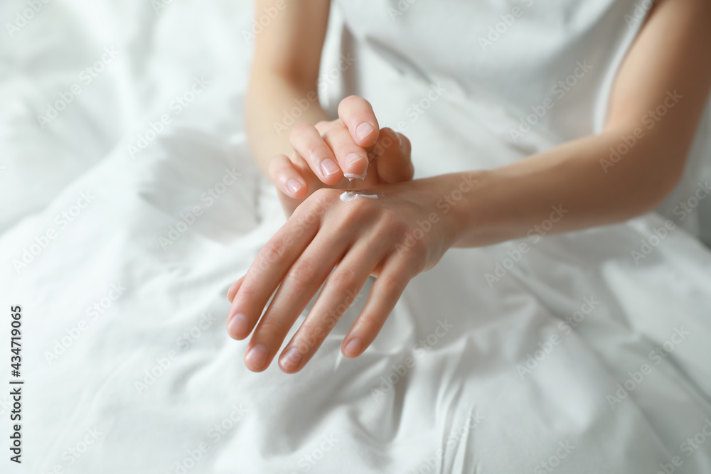 Woman applying hand cream in bed, closeup Woman applying hand cream in bed, closeup