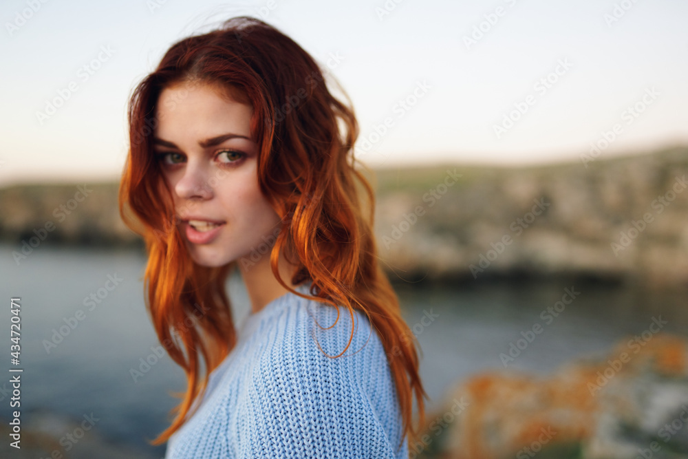 red-haired woman in sweater outdoors rocky mountains vacation