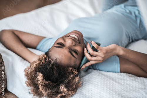 Woman communicating on smartphone while lying on bed