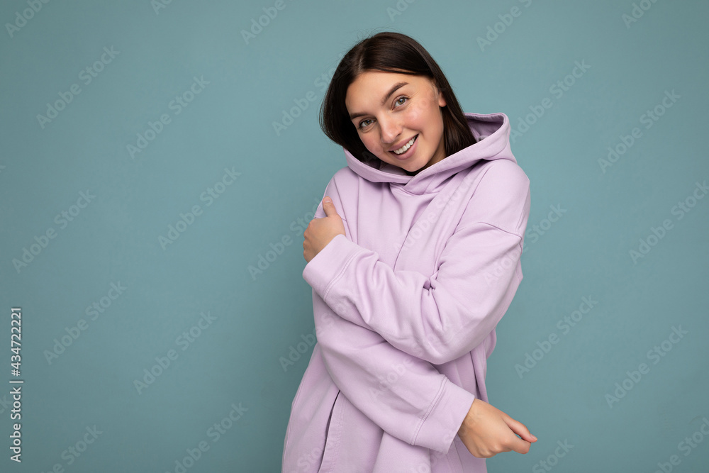 Smiling cute young beautiful brunette woman with sincere emotions isolated on background wall with copy space wearing casual stylish purple hoodie. Positive concept Smiling cute young beautiful brunette woman with sincere emotions isolated on background wall with copy space wearing casual stylish purple hoodie. Positive concept