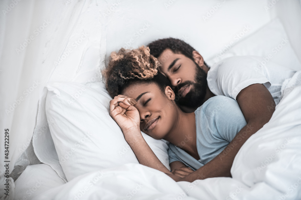 Man hugging his wife sleeping in bedroom Man hugging his wife sleeping in bedroom