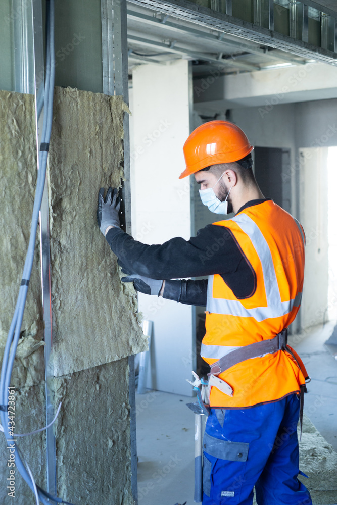 Male builder in mask putting foam into drywall Male builder in mask putting foam into drywall
