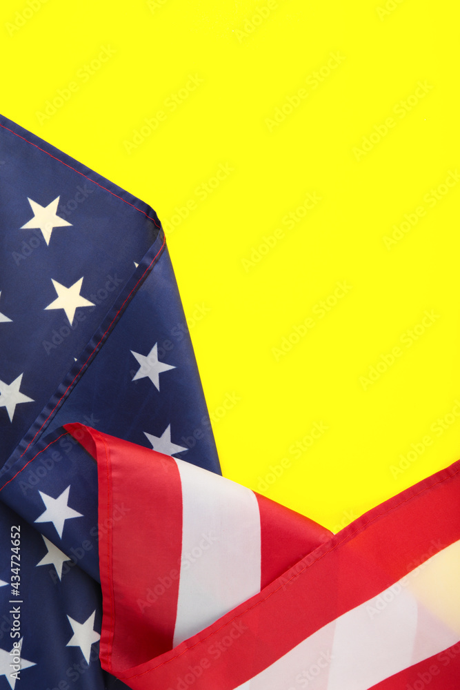 Fototapeta premium American flag on yellow background with copy space. Vertical photo