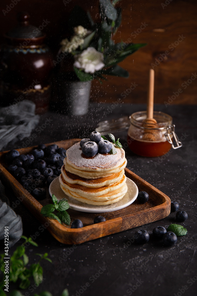 Homemade pancakes with blueberries and powdered sugar on the table close-up