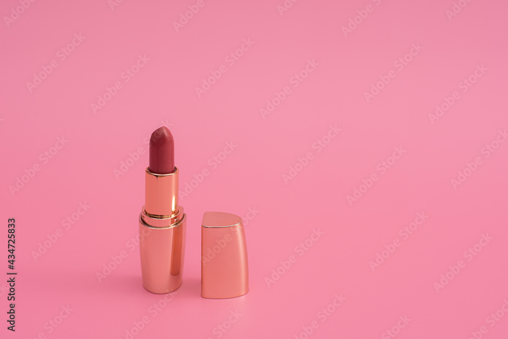 red lipstick with lid in gold. on a pink background. space for writing red lipstick with lid in gold. on a pink background. space for writing