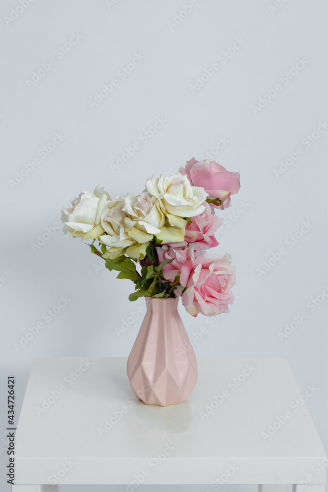Pink vase with flowers on the table on a white background. Space for text. Close-up. Pink vase with flowers on the table on a white background. Space for text. Close-up.