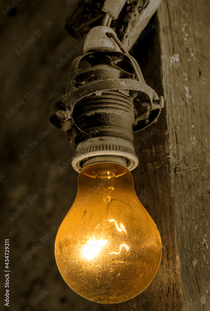An old light bulb hanging on an electrical cable on a beam. An old light bulb hanging on an electrical cable on a beam.