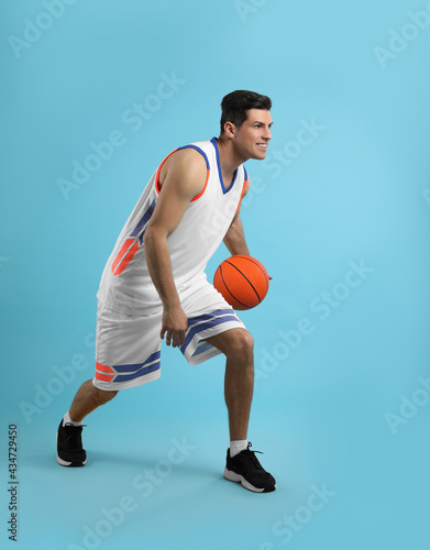 Professional sportsman playing basketball on light blue background © New Africa