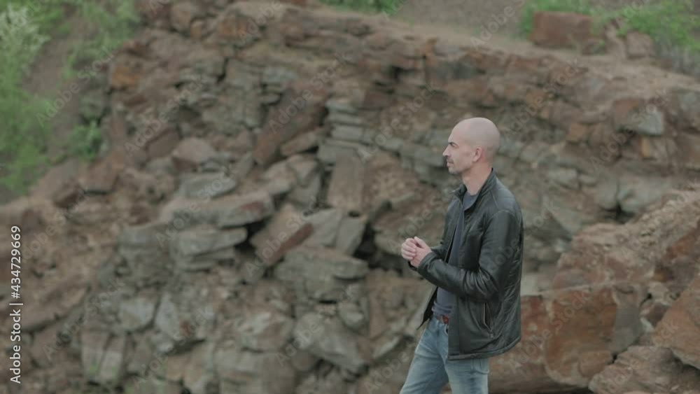 A man standing in a beautiful mountain area looks thoughtfully into the distance A man standing in a beautiful mountain area looks thoughtfully into the distance