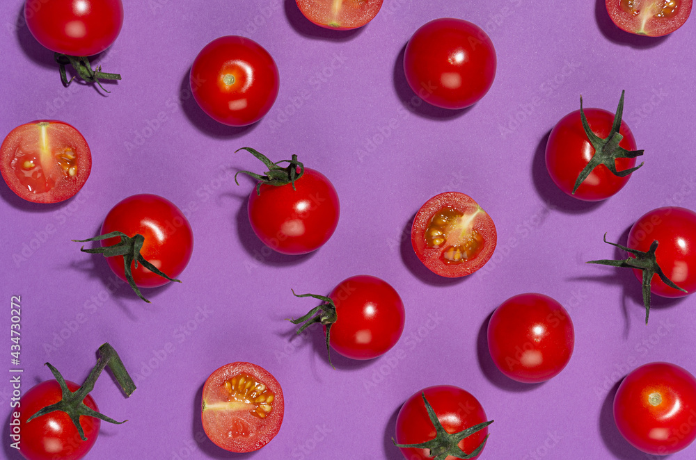 Ripe cherry tomato whole and sliced with shadow on purple background, top view, food color pattern. Ripe cherry tomato whole and sliced with shadow on purple background, top view, food color pattern.