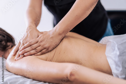 Woman receiving a back massage in a spa center. Female patient is receiving treatment by professional therapist.