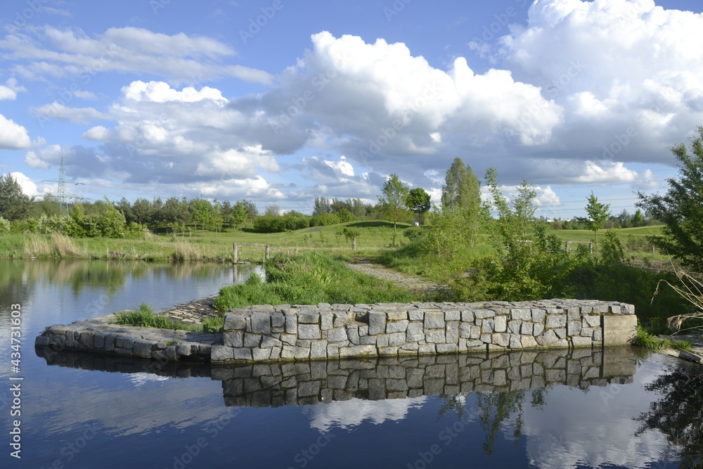 Reflection of clouds on the water surface of a pond with a stone dam Reflection of clouds on the water surface of a pond with a stone dam