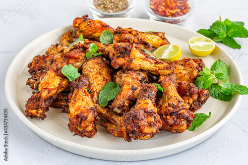 Spicy Baked Chicken Wings on a Plate Garnished with Mint Leaves Close Up