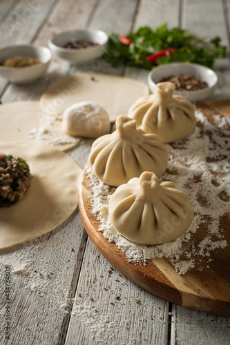 Close up to Caucasian khinkali dumplings dish served on plate. Background with ingredients and scattered spices