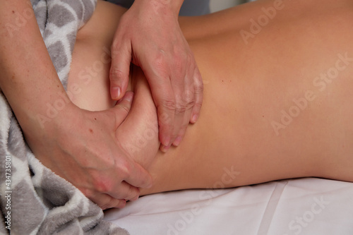 Professional massage therapist performing anti-cellulite waist massage to woman