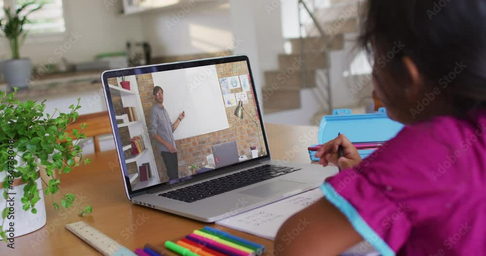 African american girl doing homework while having a video call with male teacher on laptop at home African american girl doing homework while having a video call with male teacher on laptop at home