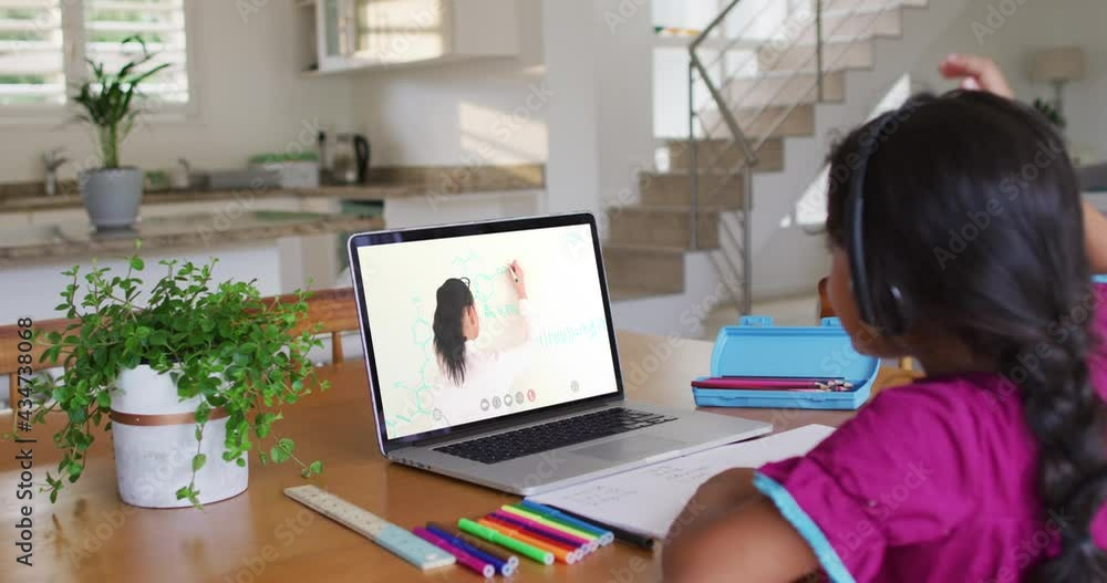 African american girl doing homework while having a video call with female teacher on laptop at home African american girl doing homework while having a video call with female teacher on laptop at home